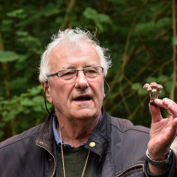 Professor Richard Fortey holds up some fungi in his left hand, while standing in Wytham Woods